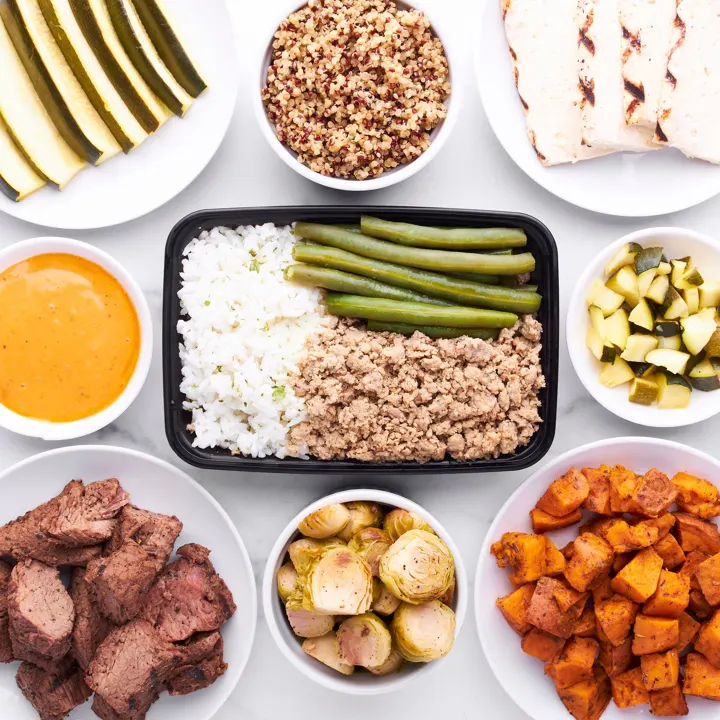 A meal prep tray of rice, green beans and ground turkey with sides around it